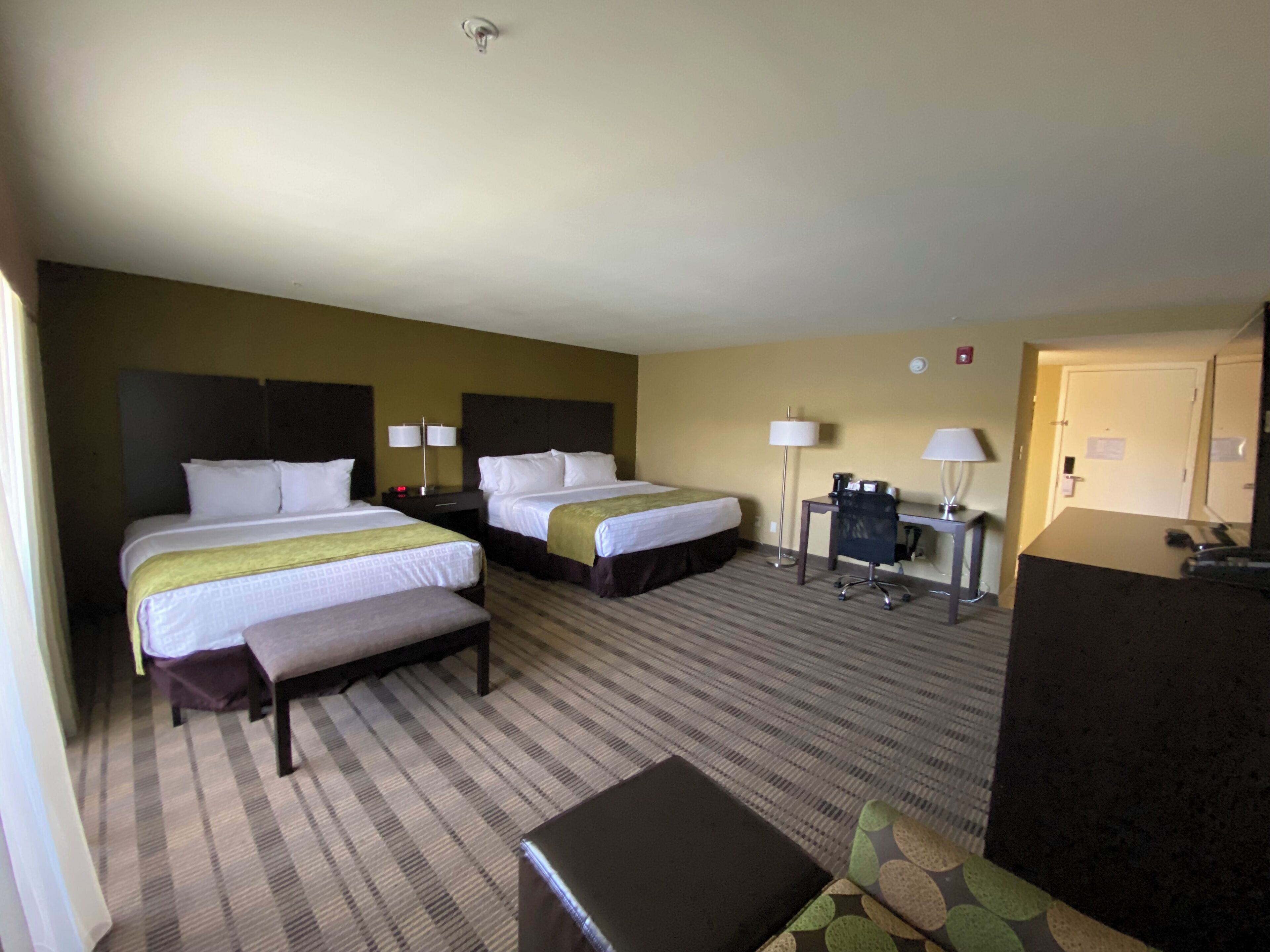 Een hotelkamer met twee bedden, een bureau, een stoel, een kleine tafel en een bank.