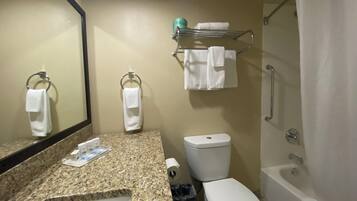Un baño con encimera de granito, un lavabo blanco, inodoro, ducha y espejo.