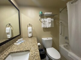 Un baño con encimera de granito, un lavabo blanco, inodoro, ducha y espejo.