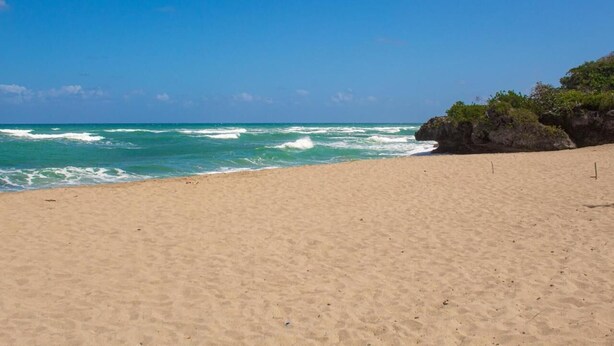 A beach with clear blue water, sandy shore, and rocky outcrops. - Linkzup Playa Laguna Villa (Sosúa)