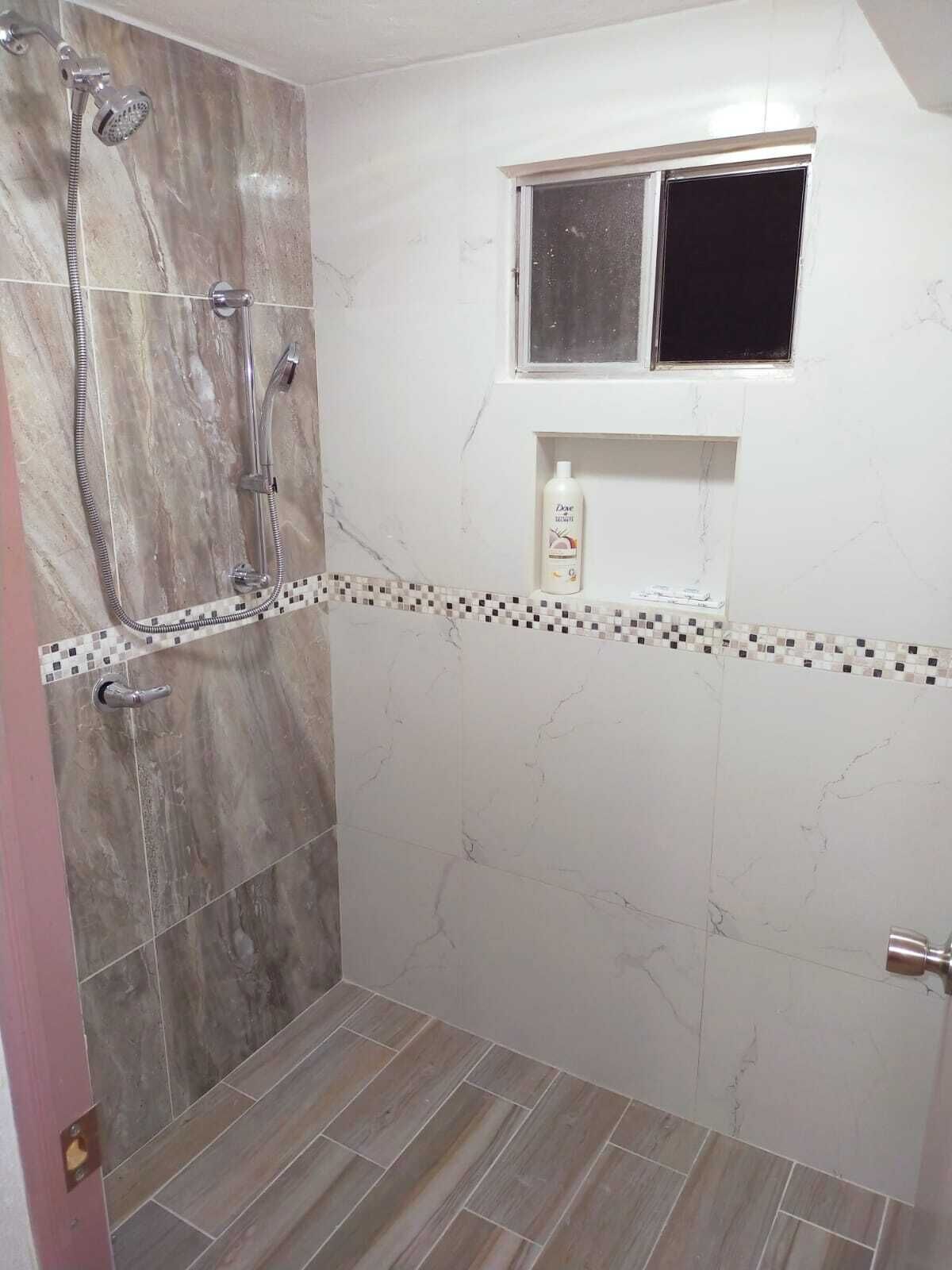 A bathroom with a shower, a window, and a shelf with toiletries.