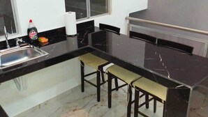 A compact kitchen with a marble countertop, a window, and a small bar area with stools. - Casa Soliman & Loft Soliman (Cancun)