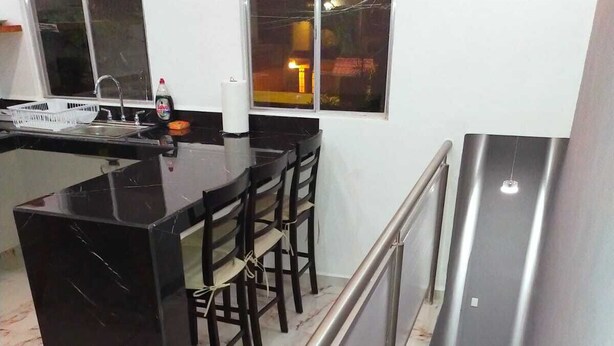 A modern kitchen with a marble countertop, a dining area with chairs, and a stainless steel staircase. - Casa Soliman & Loft Soliman (Cancun)