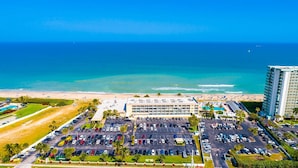 Vista aérea de un hotel con estacionamiento, playa y océano.