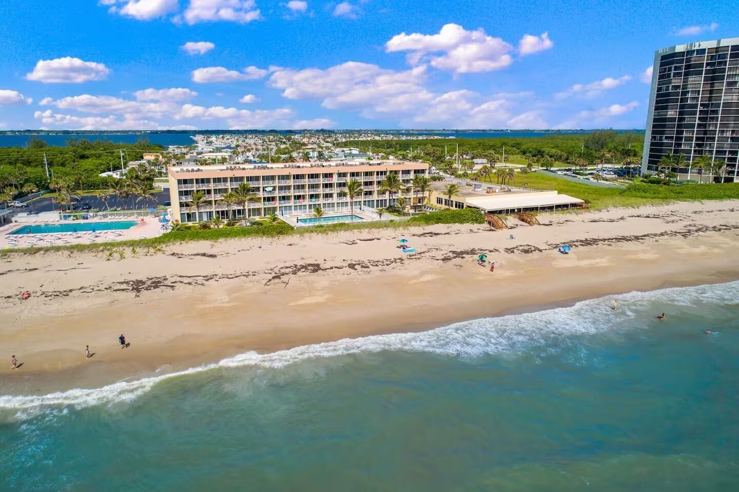 Un hôtel situé en bord de mer, doté de nombreux balcons, d’une piscine et d’un espace de plage.