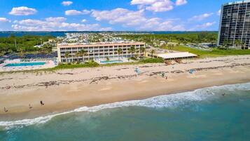 A beachfront hotel with multiple balconies, a swimming pool, and a beach area.