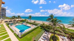Un resort con piscina, playa y palmeras.