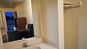 A bathroom with a white sink, wooden vanity, a mirror, and a towel rack. - Terrace Inn and Suites (Richmond)