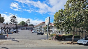 A street view of a motel with multiple rooms, a parking lot, and a clear sky. - Terrace Inn and Suites (Richmond)