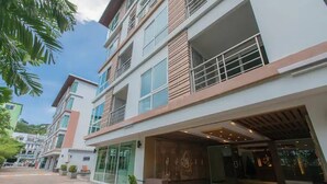 A multi-story hotel with a modern facade, large windows, and a covered entrance area. - 6-17 - 2 Bdr Condo With Balcony and Shared Pool (Patong)