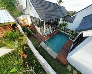 A modern house with a swimming pool, surrounded by lush greenery and a wooden deck. - Villa Sophian (Ubud)