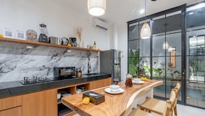 A modern kitchen with a marble backsplash, wooden cabinets, and a wooden island with seating.