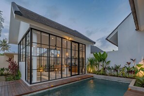 A modern house with a glass-enclosed patio, a swimming pool, and lush tropical plants. - Villa Sophian (Ubud)