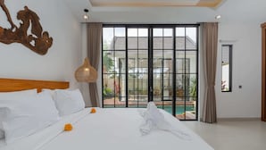 A hotel room with a large bed, a wooden headboard, a large window with a view of a swimming pool, and a hanging light fixture.