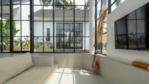 A modern interior with a white sofa, large windows, and a view of a house.