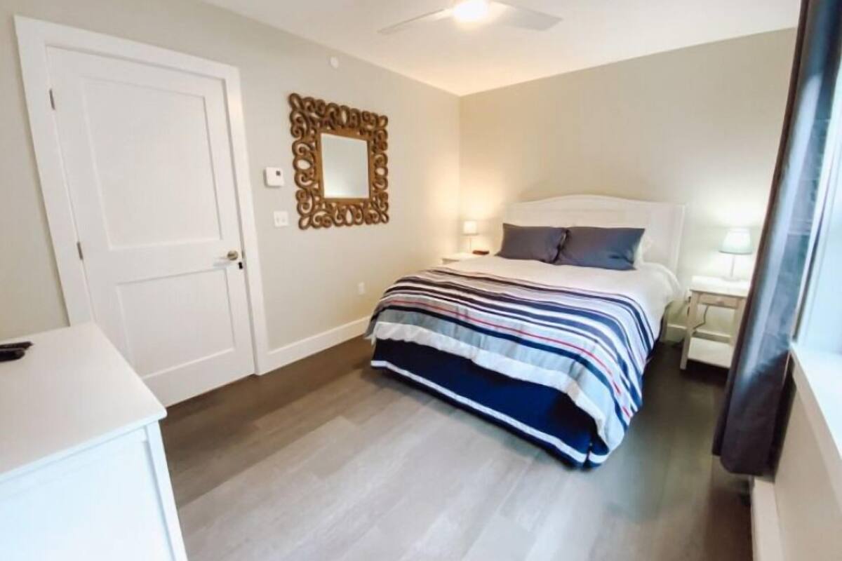 Ein Schlafzimmer mit einem Bett, Nachttischen, einem Spiegel und einem Deckenventilator.