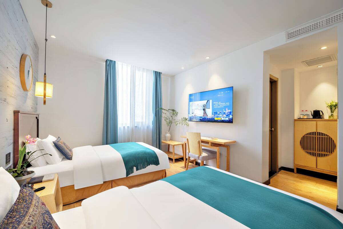 Une chambre d’hôtel avec deux lits, un bureau, une télévision et une vue sur la ville.