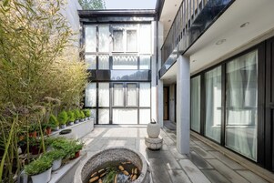 Un edificio moderno con un patio que incluye macetas con plantas y un lavadero de piedra.