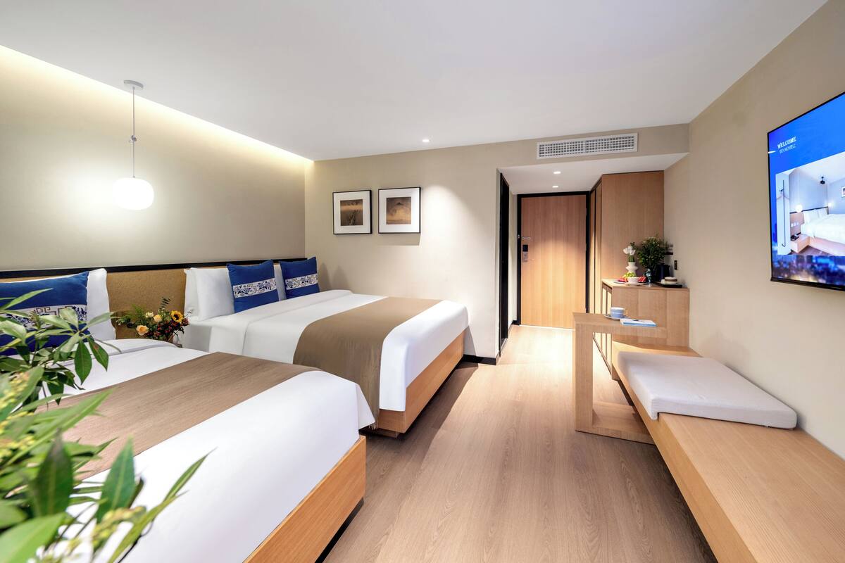 Une chambre d’hôtel avec deux lits, un bureau, une télévision et un petit coin salon.