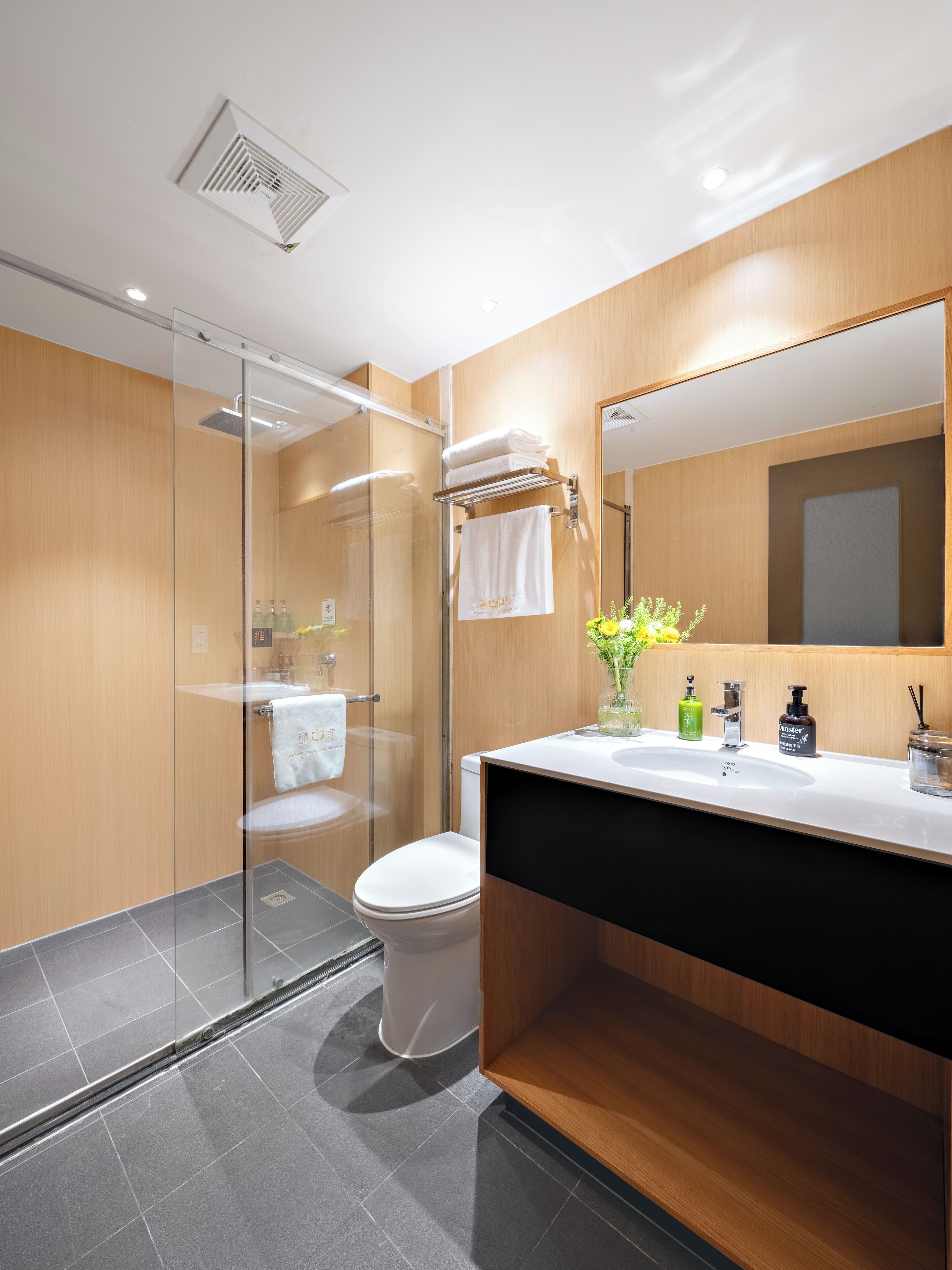 A modern bathroom with a glass shower enclosure, a white toilet, and a vanity with a mirror.