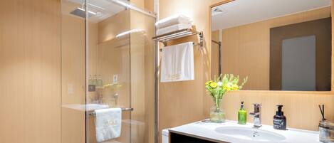Un baño moderno con cabina de ducha de vidrio, inodoro blanco y tocador con espejo.
