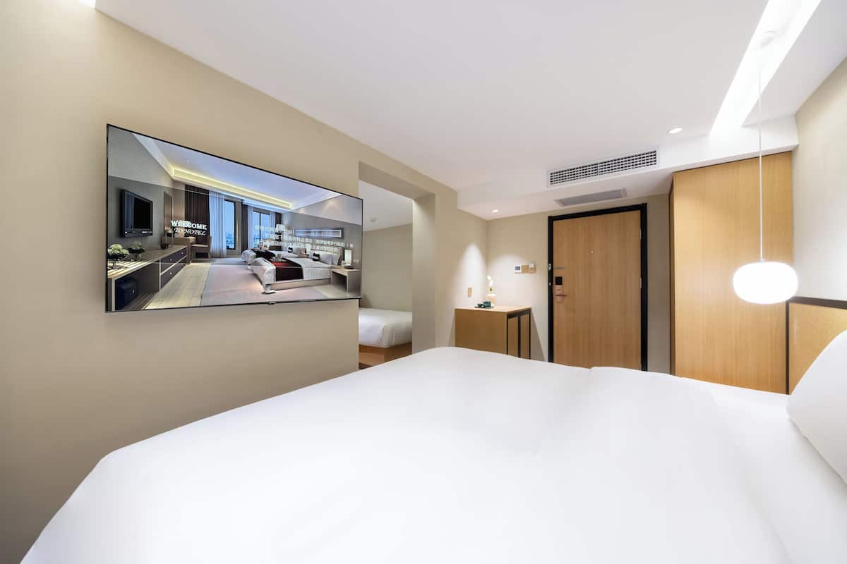 Une chambre d’hôtel moderne dotée d’un grand lit, d’un téléviseur fixé au mur, d’un bureau et d’une armoire.
