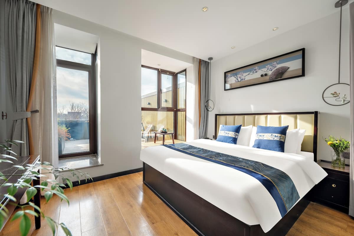 Une chambre d’hôtel moderne avec un grand lit, une vue sur le balcon extérieur et un tableau au mur.