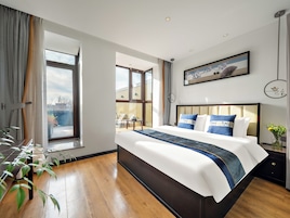 Un hotel moderno con una cama grande, vista al balcón exterior y un cuadro en la pared.