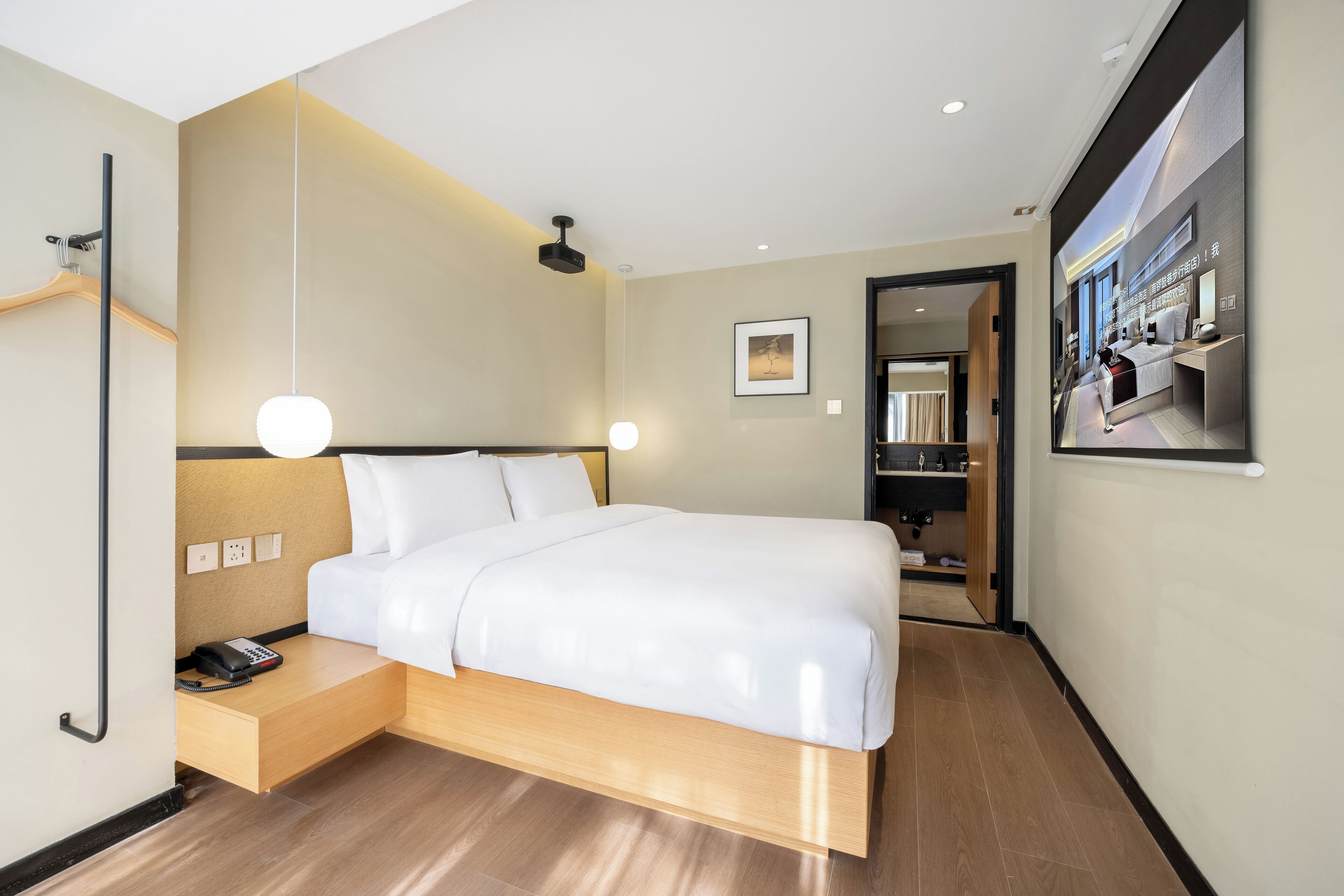 A modern hotel room with a wooden bed, bedside table, and a phone.