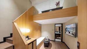 A modern hotel lobby with a wooden staircase, a reception desk, a small seating area, and a large mirror reflecting the interior. - Beijing Aaliyah Wang Fu Jing Forbodden City Boutique Hotel (Beijing)