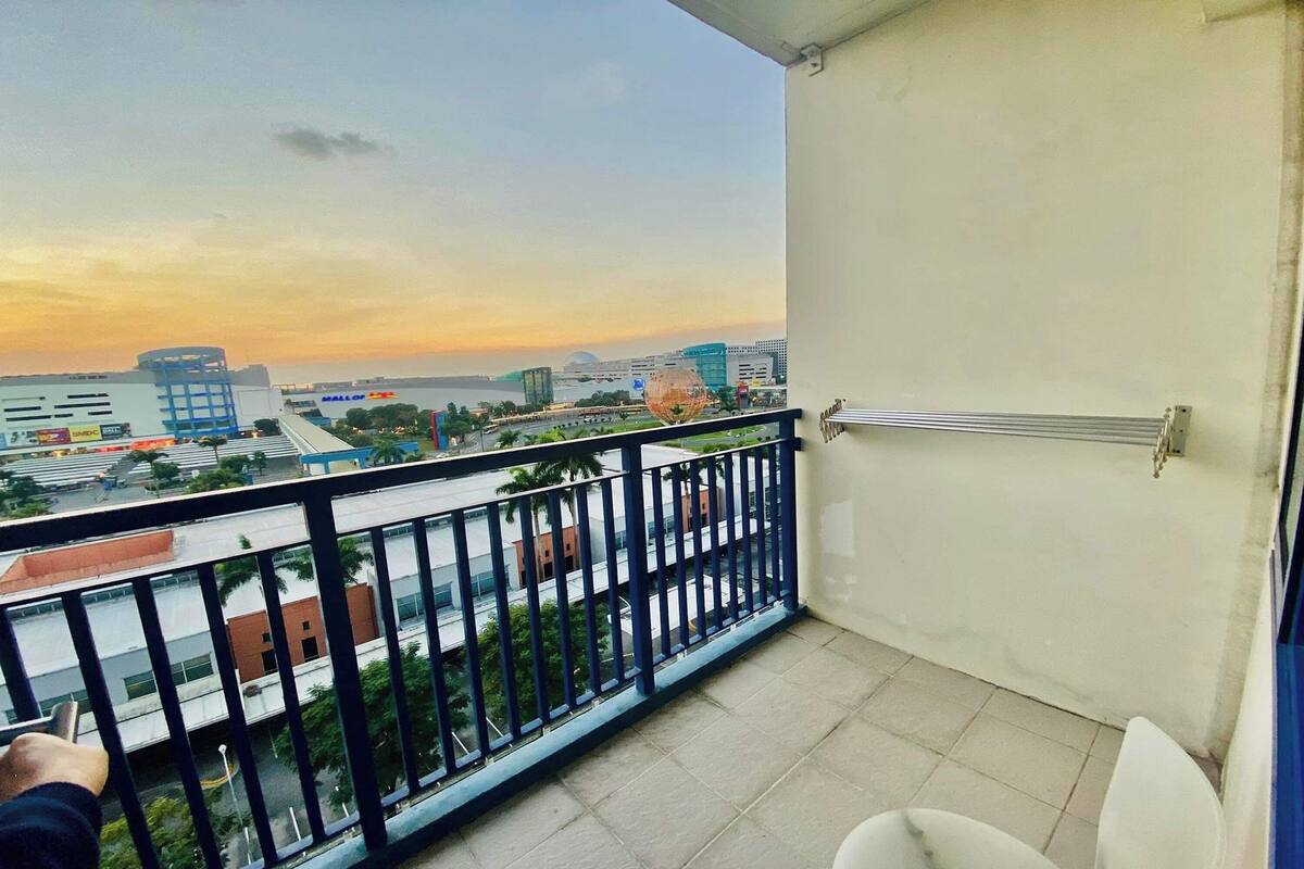 A balcony with a view of a cityscape, including a mall and buildings.