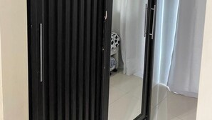 A room with a sliding door closet, a shower area, and a visible bed with a patterned blanket. - Madison's Place at Sea MOA (Pasay)