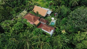 An aerial view of a residential area with multiple houses surrounded by dense tropical vegetation. - Campuhan Guesthouse (Penebel)
