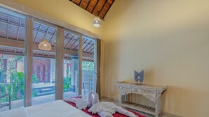 A hotel room with a large bed, a wooden ceiling, a white console table, and a view of the outside. - Campuhan Guesthouse (Penebel)