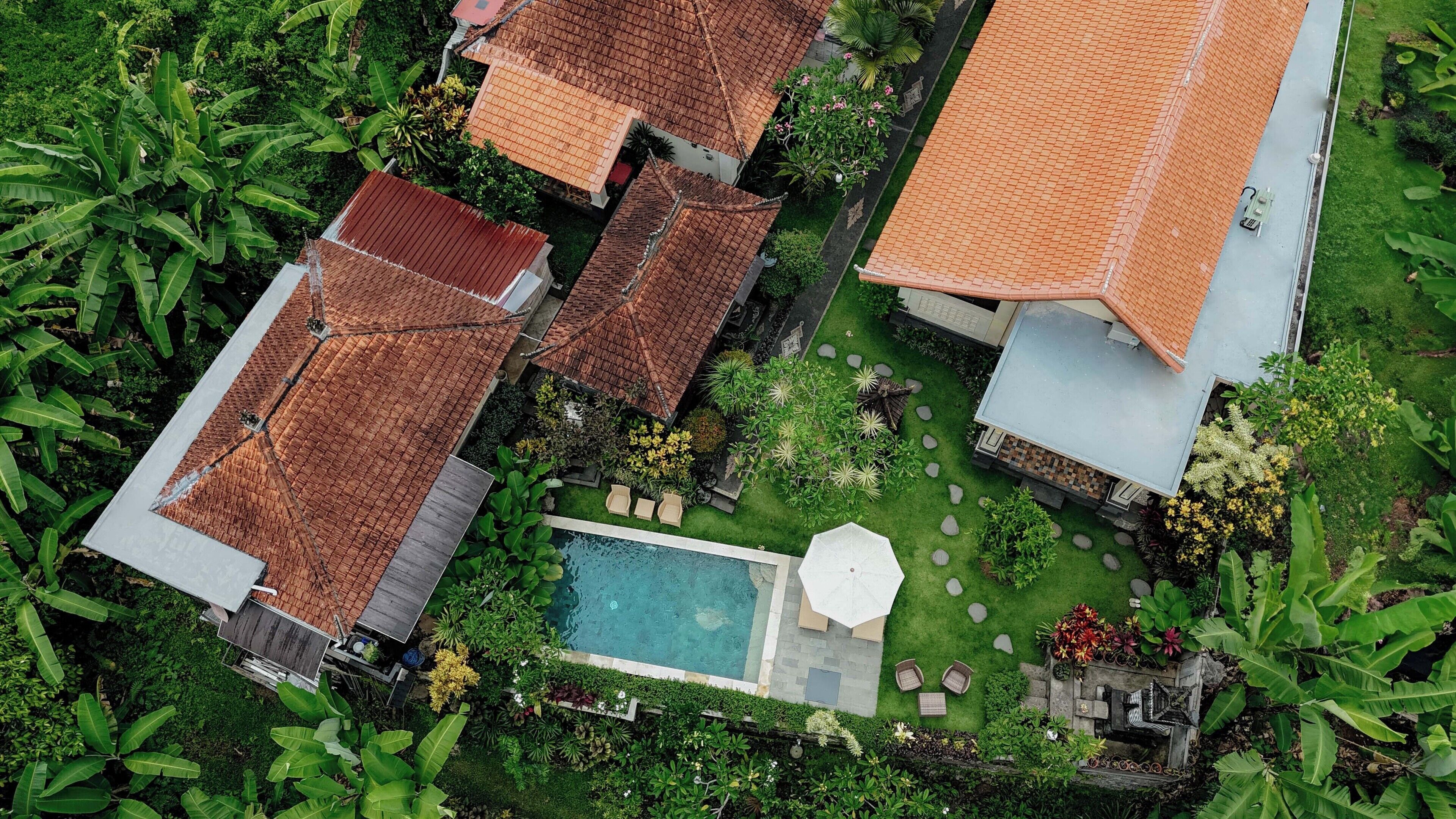 Vista aérea de una zona residencial con varias casas, una piscina y abundante vegetación.