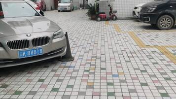 Een parkeerplaats met een BMW, een scooter en een witte bestelwagen.