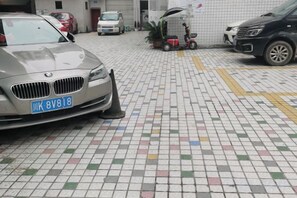 A parking area with a BMW car, a scooter, and a white van.