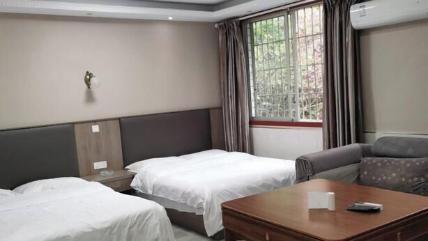 Una habitación de hotel con dos camas individuales, un sofá, una mesa de madera y una ventana con cortinas.