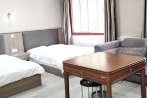 Ein Hotelzimmer mit einem Bett, einem Sofa, einem kleinen Holztisch und einem Fenster mit Vorhängen.