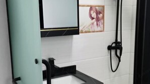 Un baño con un lavamanos negro, un espejo y una ducha.