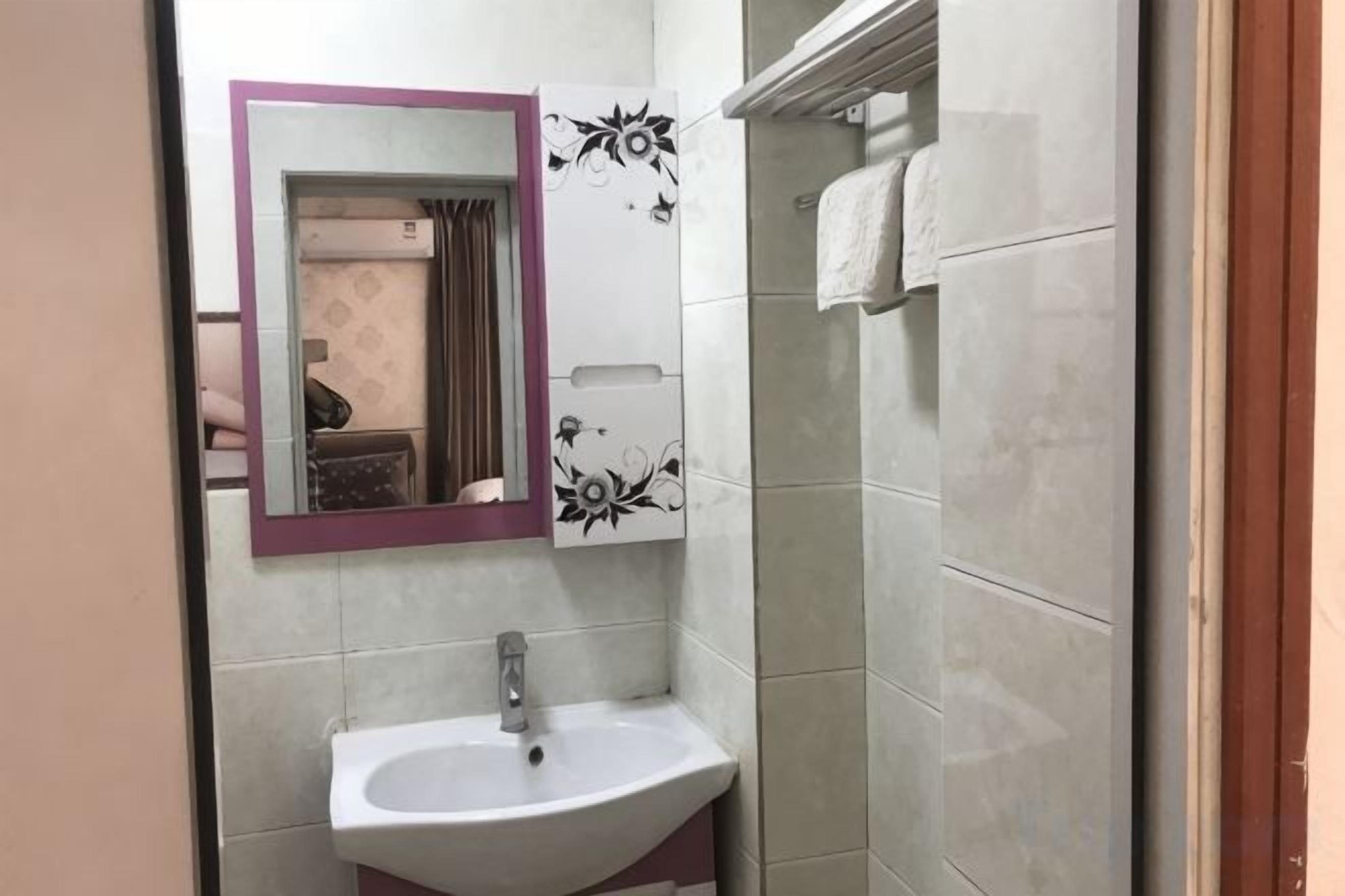 A bathroom with a sink, mirror, and tiled walls.