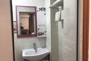 Un baño con lavamanos, espejo y paredes con azulejos.
