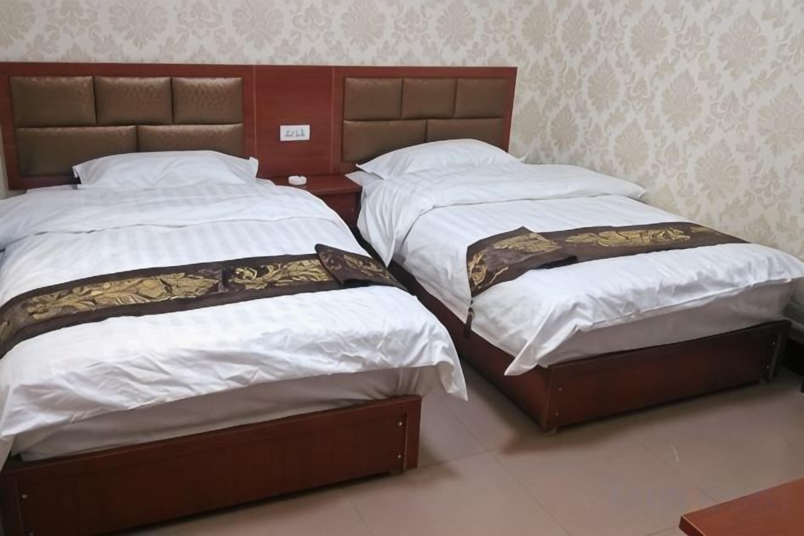 Uma cama de casal com cabeceira, mesa de cabeceira e painel de controle fixado na parede.