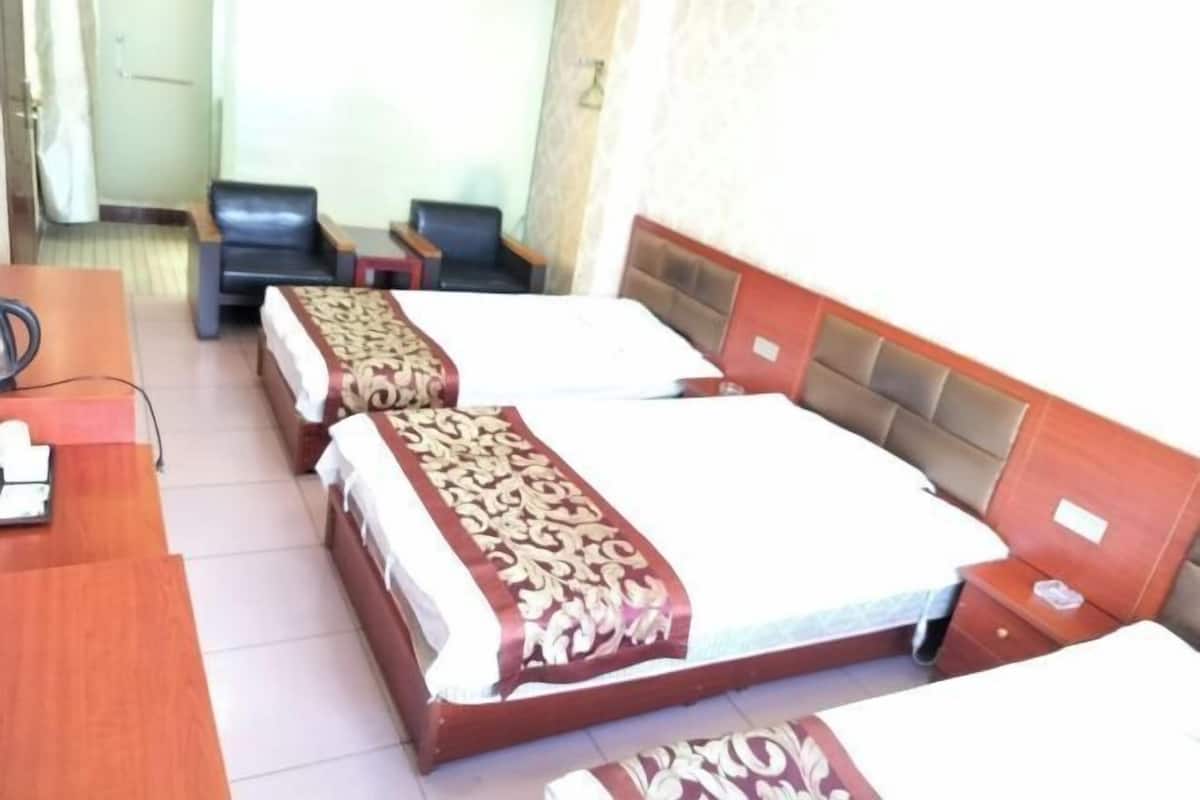 A hotel room with two beds, a desk, and a chair.