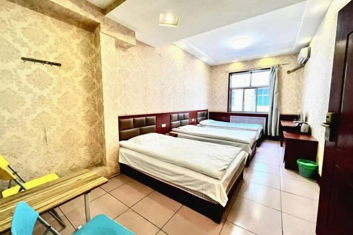 A room with two beds, a small desk, a chair, and a window.