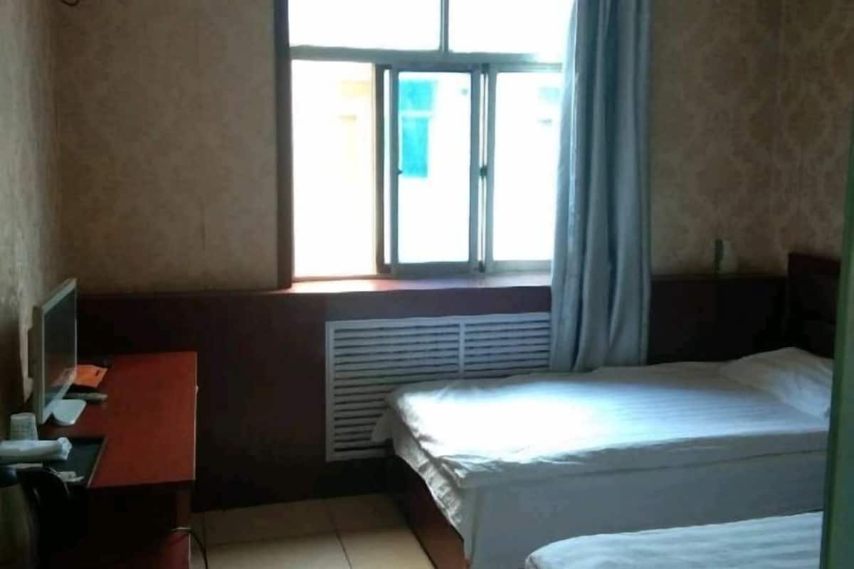 A room with a bed, a desk, a window, and a radiator.