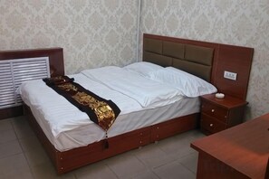 A standard hotel room with a bed, bedside table, and a small desk. - Lanzhou Yunhai Hotel (Lanzhou)