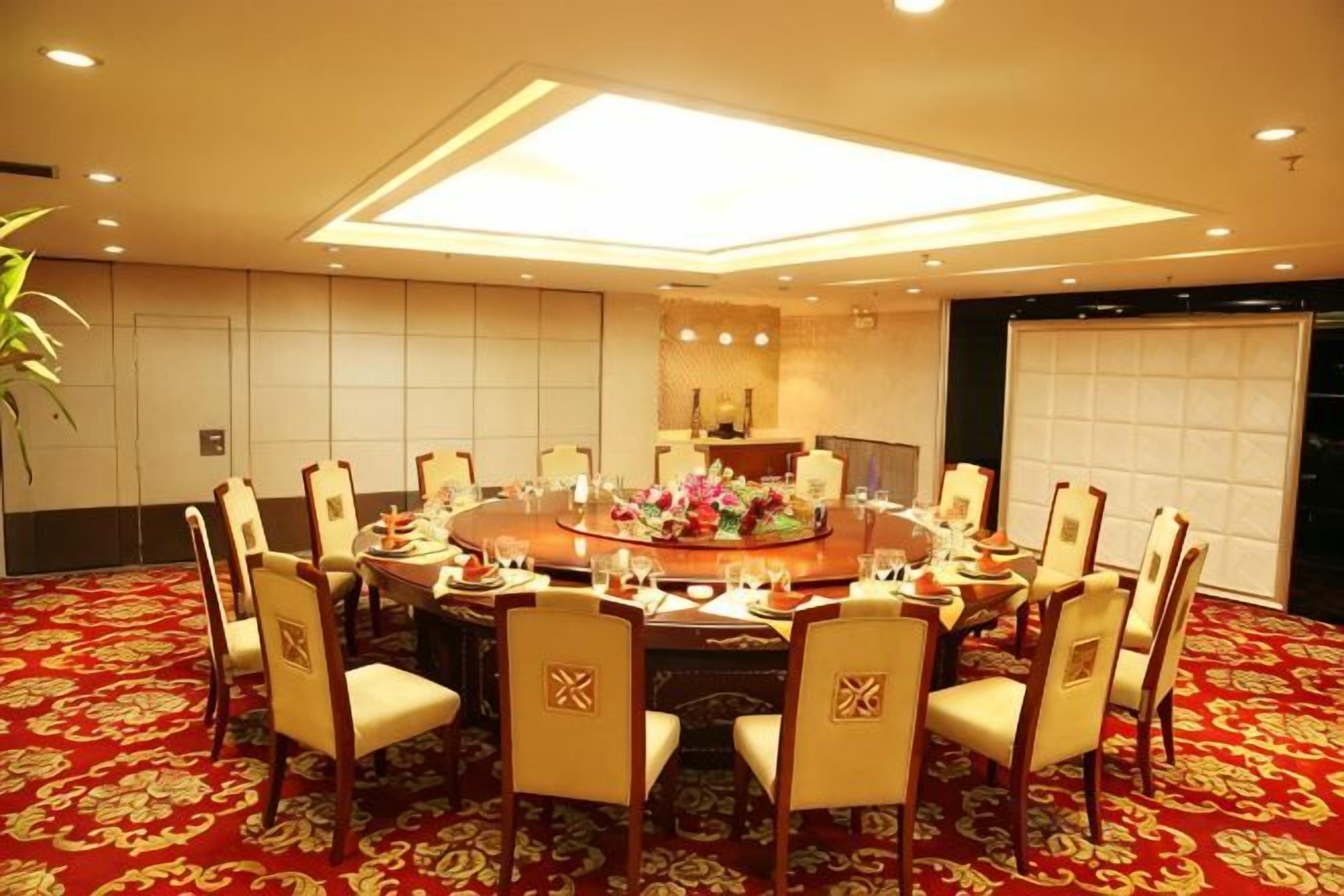 A conference room with a round table, chairs, and a carpeted floor.