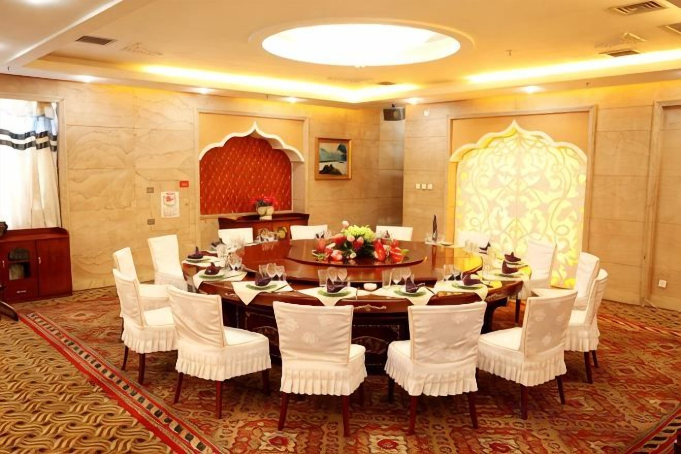 A conference room with a round table, white chairs, and a carpeted floor.