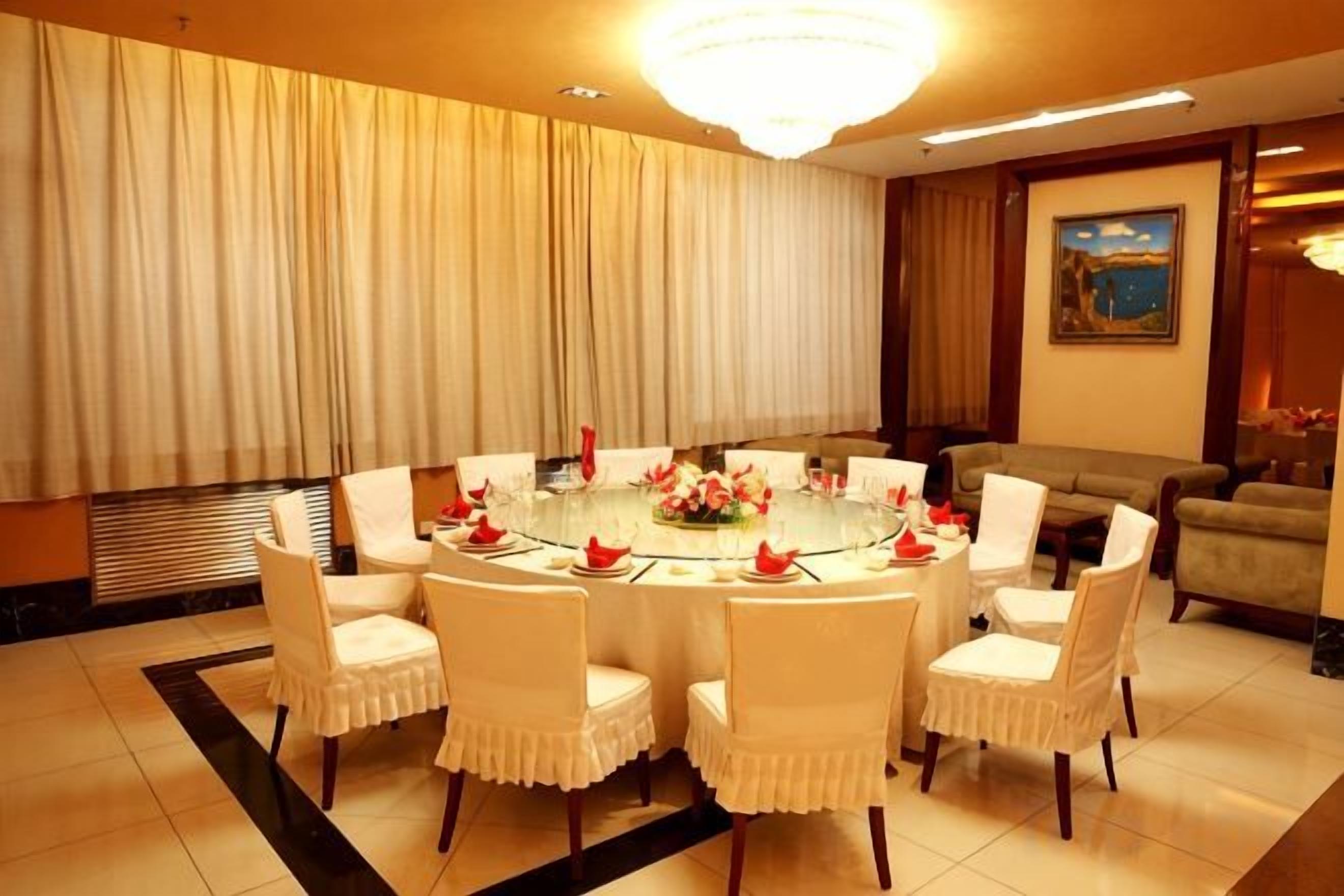 Un comedor con una mesa redonda, sillas blancas y una lámpara de araña.